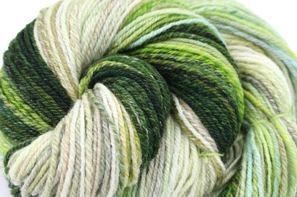 A close up view of a one of a kind, hand dyed gradient skein of multicolored Evergreen, Olive, Lime Green, Seafoam Green, Light Grayish Brown, and Cream self-striping wool Yarn. 