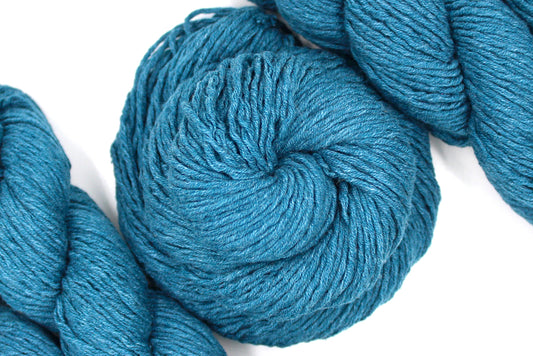 A skein of Vegan, Dark Greenish Teal, Cotten blend, Worsted Weight Yarn recycled by hand from unwanted sweaters swirled attractively in the center of the frame. 