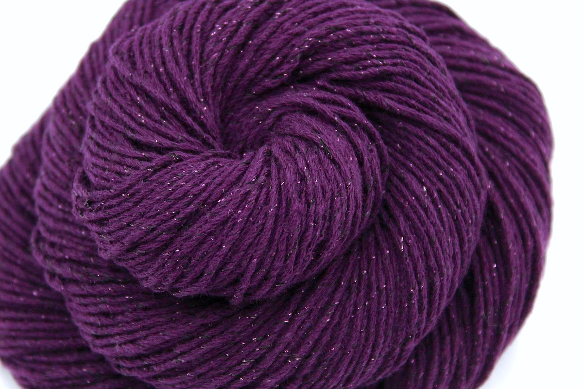 A close up shot of a skein of Vegan, Deep Plum Purple, Cotton/ Polyester/ Sparkle Fiber, Sport weight Yarn recycled by hand from unwanted sweaters beautifully coiled in the center of the frame. 