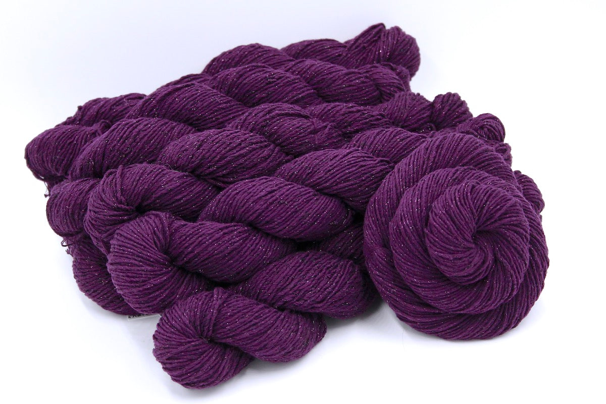 Several skeins of Vegan, Deep Plum Purple, Cotton/ Polyester/ Sparkle Fiber, Sport weight recycled by hand from unwanted sweaters stacked on top of each other attractively. 