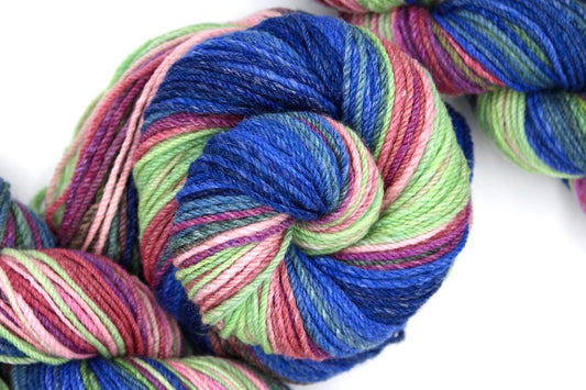 A one of a kind, hand dyed gradient skein of multicolored Navy Blue, Royal Blue, Teal, Green, Olive Green, Magenta, Salmon, Pastel Pink and Mint Green self-striping wool Yarn coiled attractively in the center of the frame. 