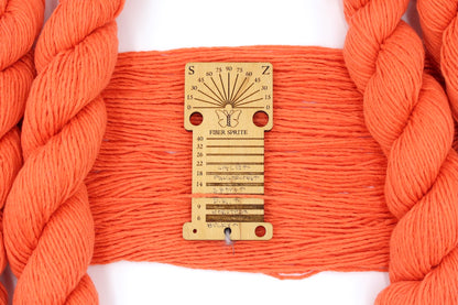 A skein of Vegan, Neon Tangerine Orange, Cotton/ Nylon, Dk Weight Yarn recycled by hand from unwanted sweaters draped over a Llama shaped Yarn weight tool. 