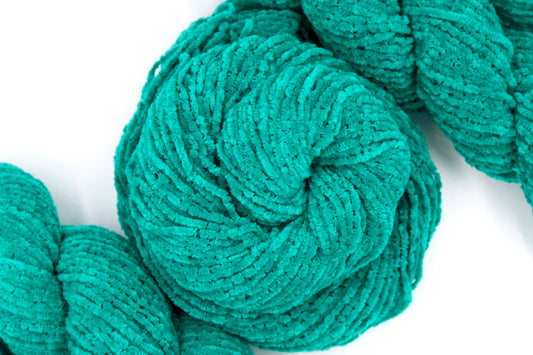 A skein of Vegan, Bright Teal, 100% Acrylic, Worsted Weight Chenille Yarn recycled by hand from unwanted sweaters swirled attractively in the center of the frame. 