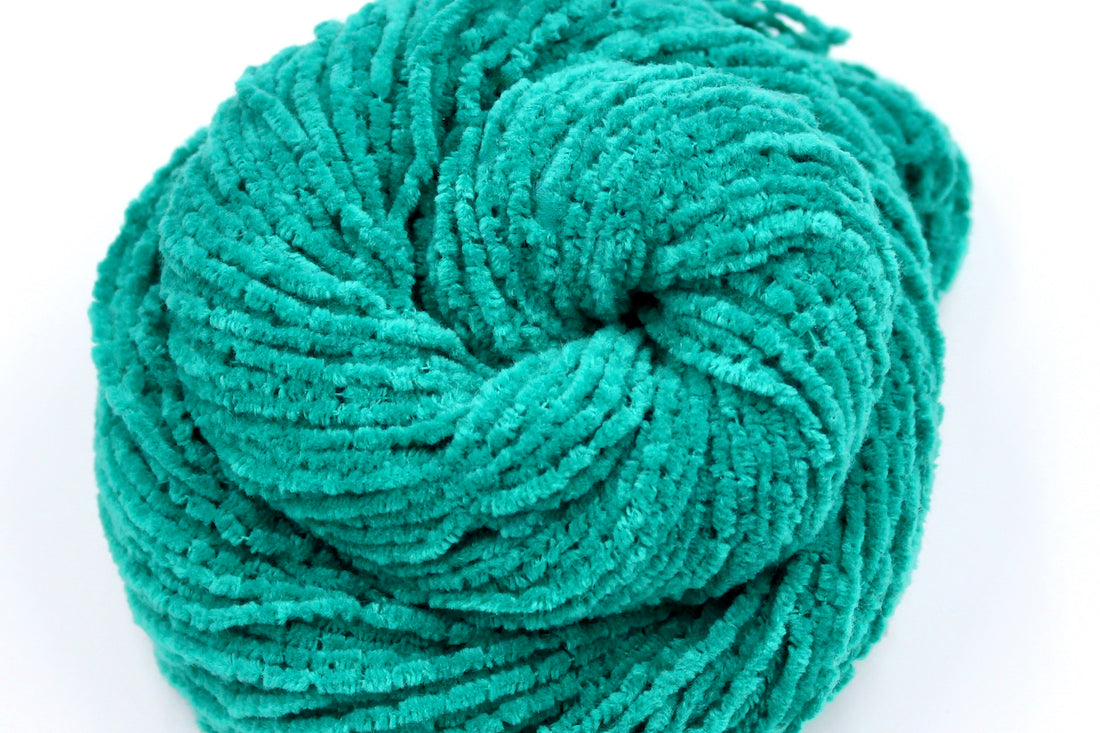 A close up shot of a skein of Vegan, Bright Teal, 100% Acrylic, Worsted Weight Chenille Yarn recycled by hand from unwanted sweaters beautifully coiled in the center of the frame. 
