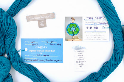 A skein of Vegan, Teal blue, 100% Cotton, Sport Weight yarn encircling the sweater labels it was recycled from, as well as the hand written yarn tags detailing the specs of this recycled yarn to help you make your next project! 