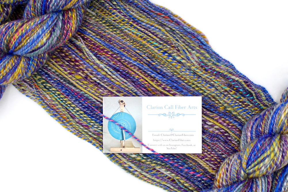 A one of a kind, Worsted Weight, hand dyed variegated skein of Rainbow multicolored self-striping Hand spun Yarn, made with Hand Dyed Wool and Bamboo, draped diagonally across the frame, so you can really see the color play. 