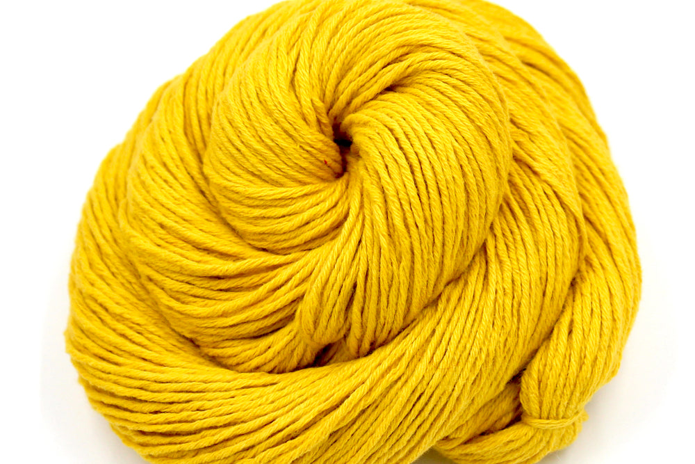 A close up shot of a skein of Vegan, Mustard Yellow, 100% Cotton, Sport Weight Yarn recycled by hand from unwanted sweaters beautifully coiled in the center of the frame. 